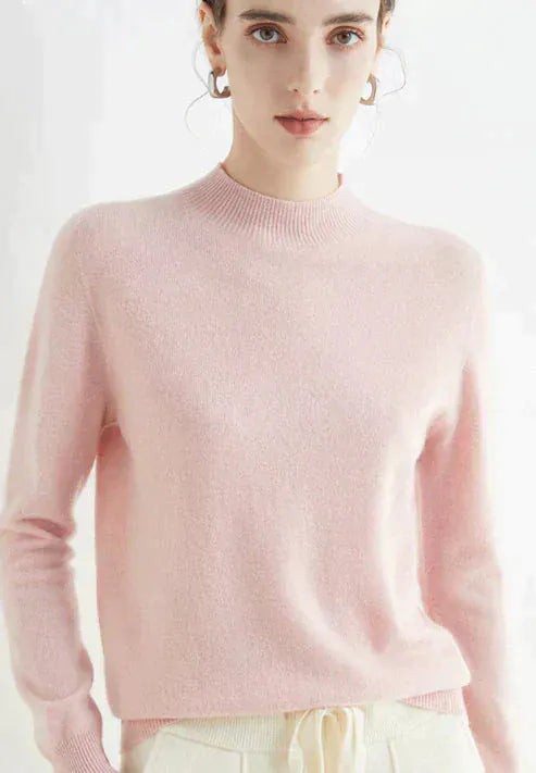 Close up, model wearing a light pink cashmere mock-neck jumper with ribbed collar and cuffs, light coloured pants