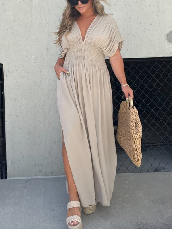 Front view of model wearing an elegant summer maxi dress with side split and pockets, holding a woven bag