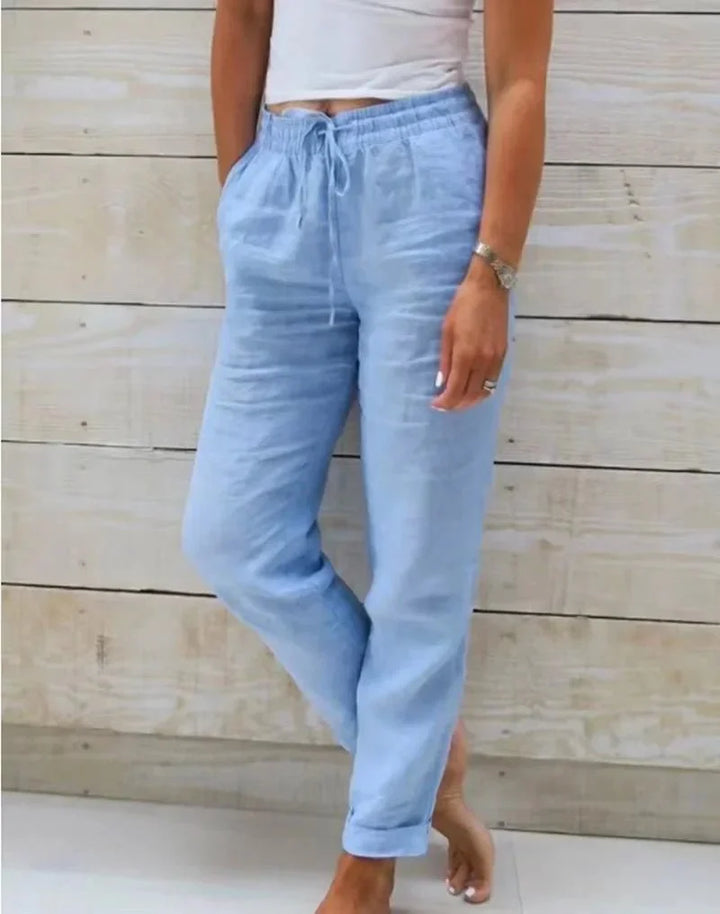 Close up view of light blue cotton linen summer pants with a high waist, worn by model