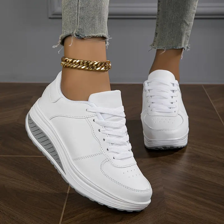 Front view, worn by model, of white Myrtle comfort sneakers with thick grey and white soles, paired with an ankle bracelet