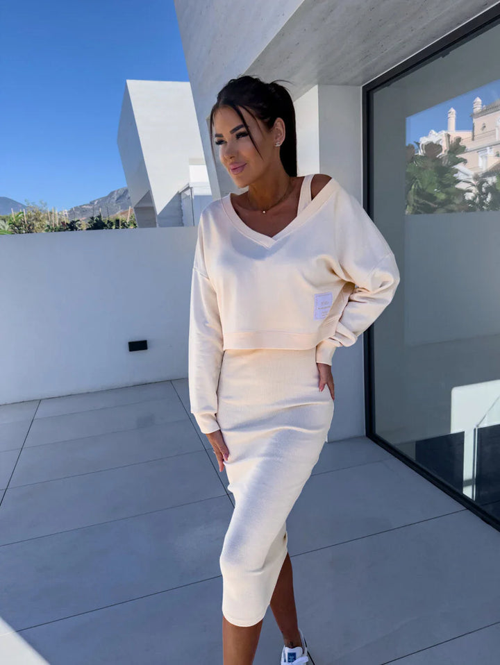 Three quarter view of a model wearing a casual cream sweatshirt and dress set with a square patch on the top