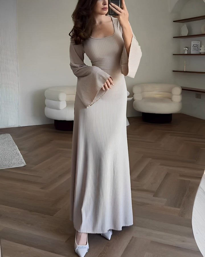 Front view of a model in an elegant knit maxi dress with a square neckline, flare sleeves, and ribbed texture