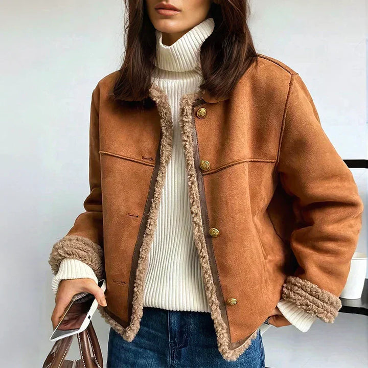 Camel brown sheepskin buttoned jacket worn open over a white turtleneck