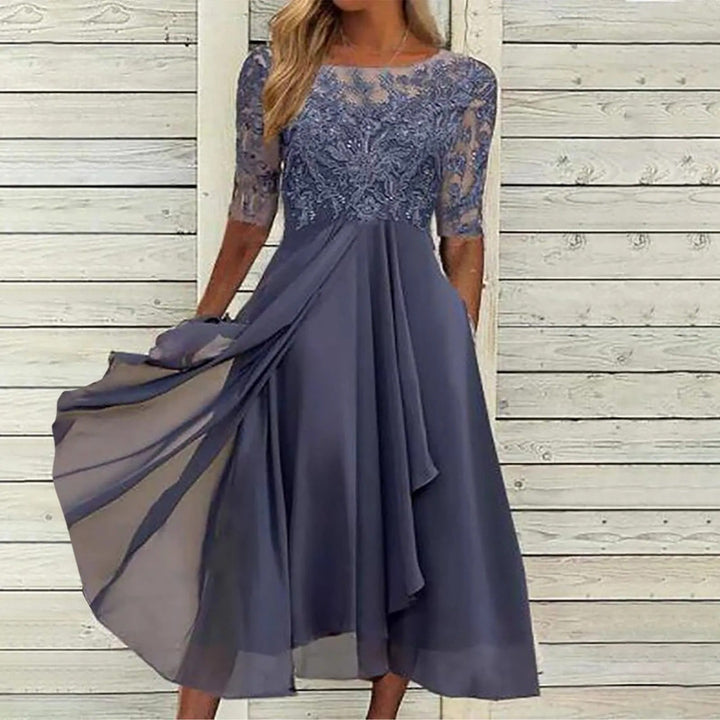 Three quarter view of a model in a blue lace dress with a flowing viscose skirt and sheer sleeves