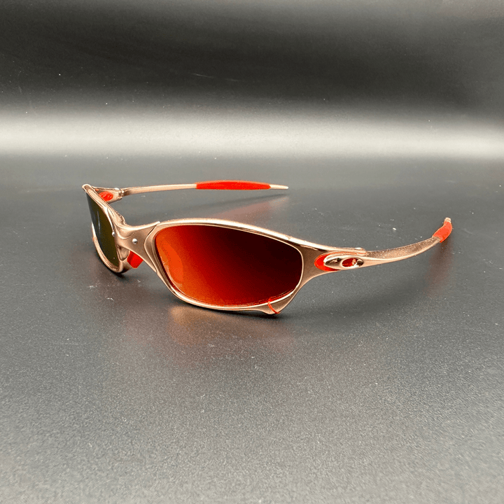 Three quarter view of Ecliptic polarized sunglasses with gold frame and red lenses on a black background