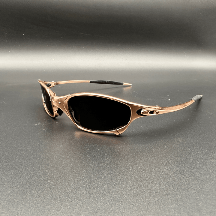 Three quarter view of Ecliptic polarized sunglasses with gold frame and dark lenses on a black background