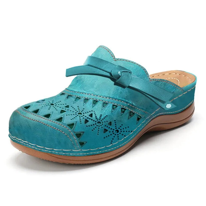 Side view of a blue wedge heel slip-on sandal with detailed cut-outs and a knotted strap