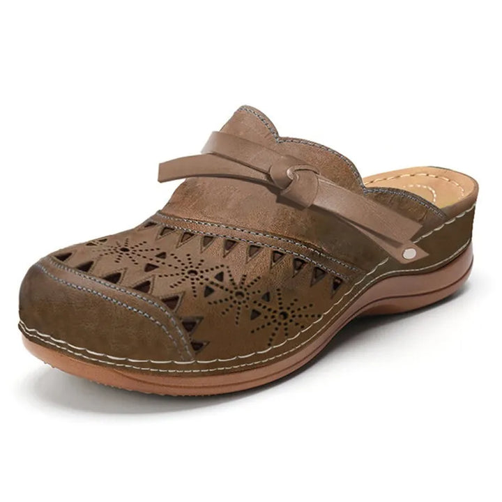 Side view of a brown wedge heel slip-on sandal with detailed cut-outs and a knotted strap