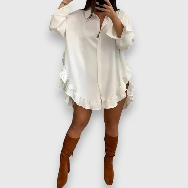 Front view of a model wearing a white elegant blouse dress with a ruffled hem and brown knee-high boots
