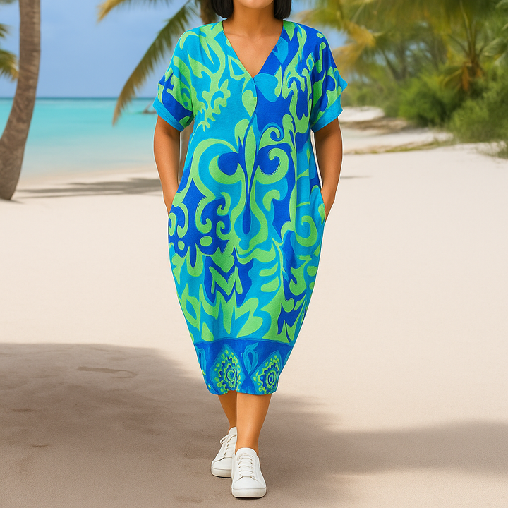 Front view of a model wearing the Breezy Printed V-Neck Midi Dress with hands in pockets on a beach