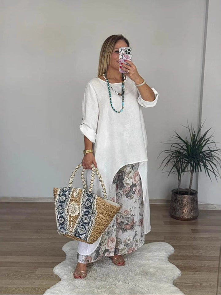 Front view of a model wearing a long-sleeve top and floral printed pants set, holding a patterned straw bag