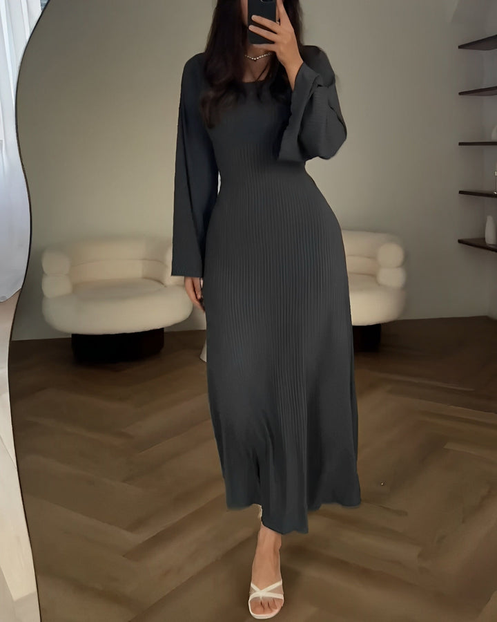Front view of a model wearing a dark grey elegant knit maxi dress with a round neckline and flare sleeves