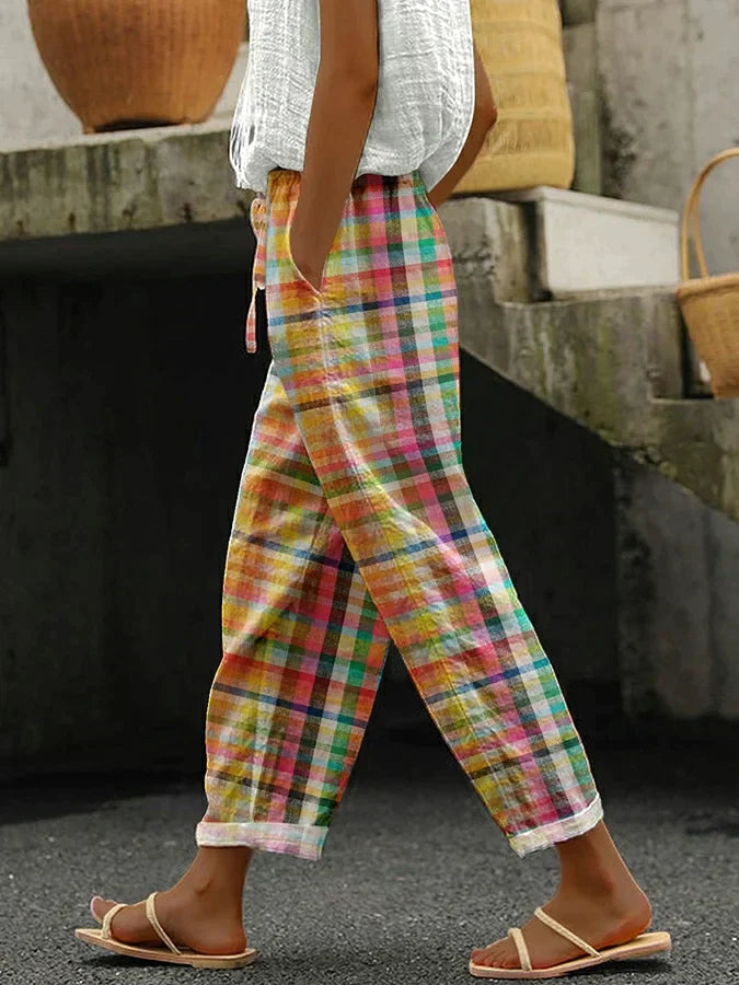 Side view, model wearing colourful plaid relaxed fit elastic waist trousers with a tie closure and rolled cuffs