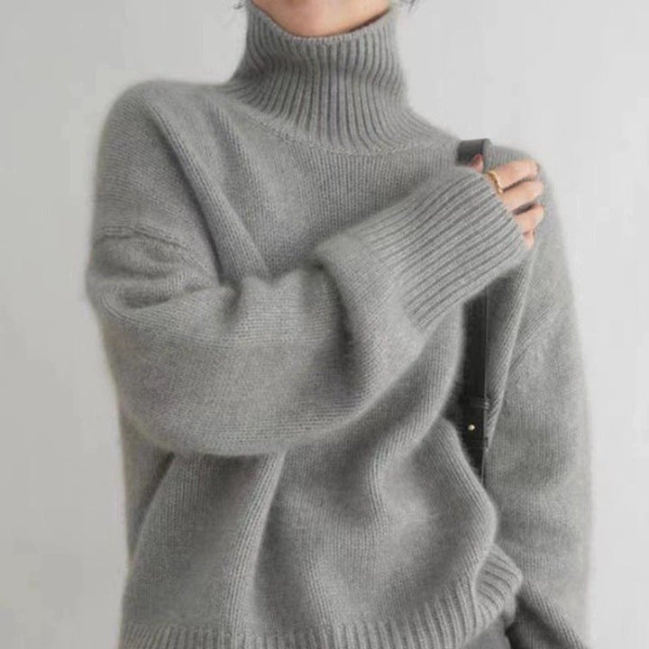 Side view of a model wearing a grey 100% wool turtleneck sweater with a ribbed hem and cuffs