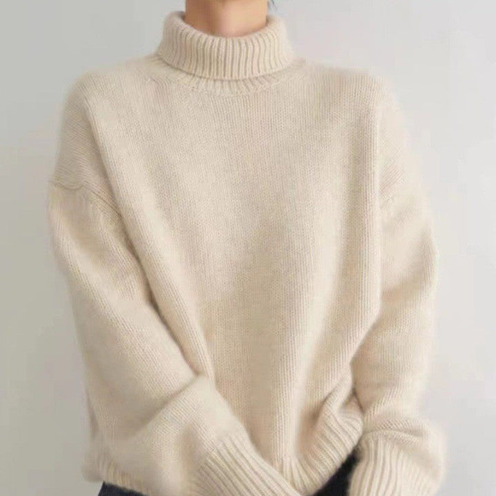 Front view of a model wearing a cream 100% wool turtleneck sweater with ribbed cuffs and collar