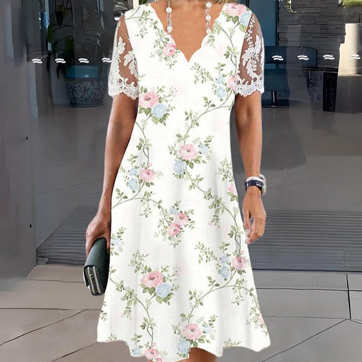 Front view of a model wearing a white floral graphic midi dress with pink and blue flowers and boho lace detail sleeves