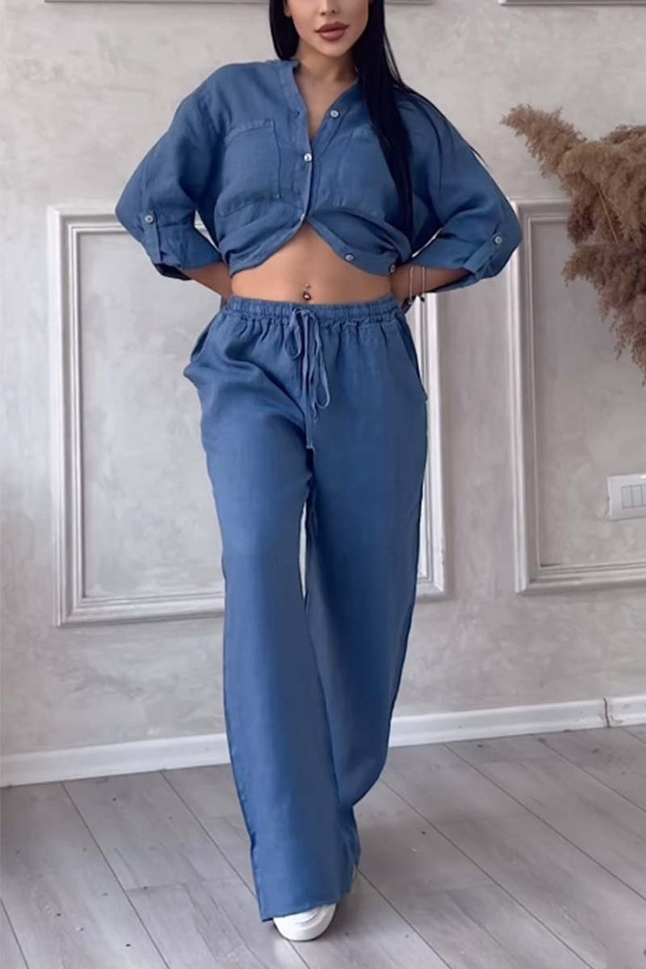 Front view of a model in a denim blue long sleeve blouse and wide leg pants set