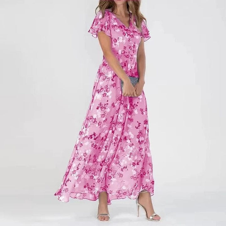 Three quarter view, model in a colourful maxi summer dress with a V-neck and short flutter sleeves, holding a clutch