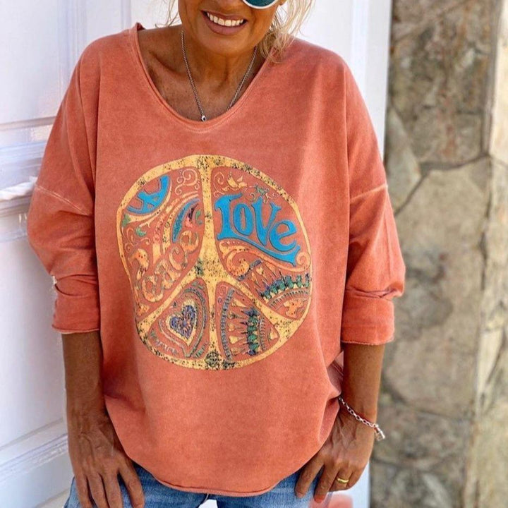 Front view of a model wearing an orange sweatshirt with a vintage peace sign graphic and "Love" text