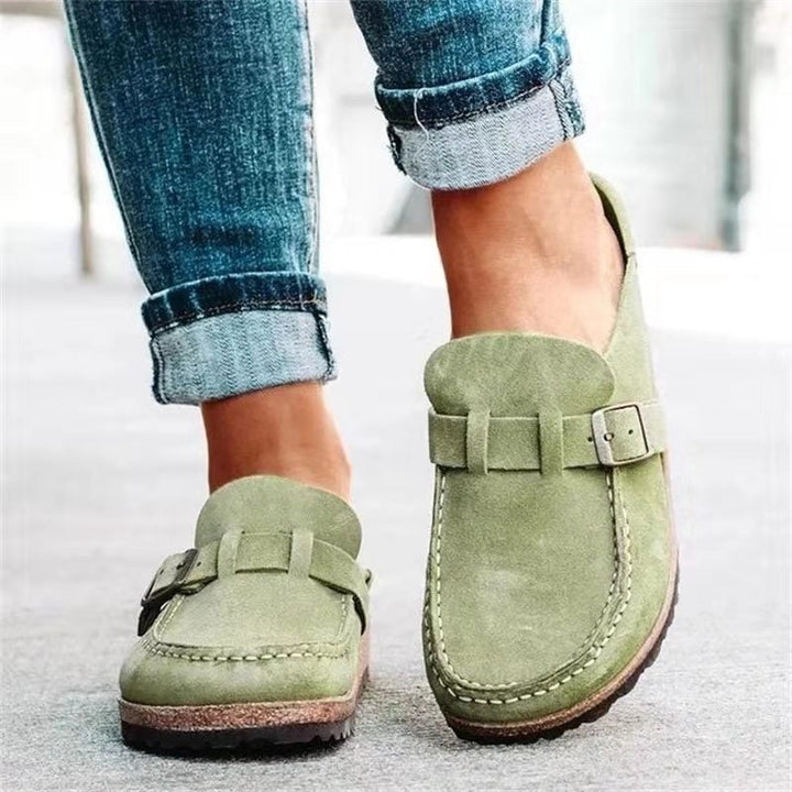 Worn by model of green suede loafers with buckle and white stitching detail, paired with cuffed jeans