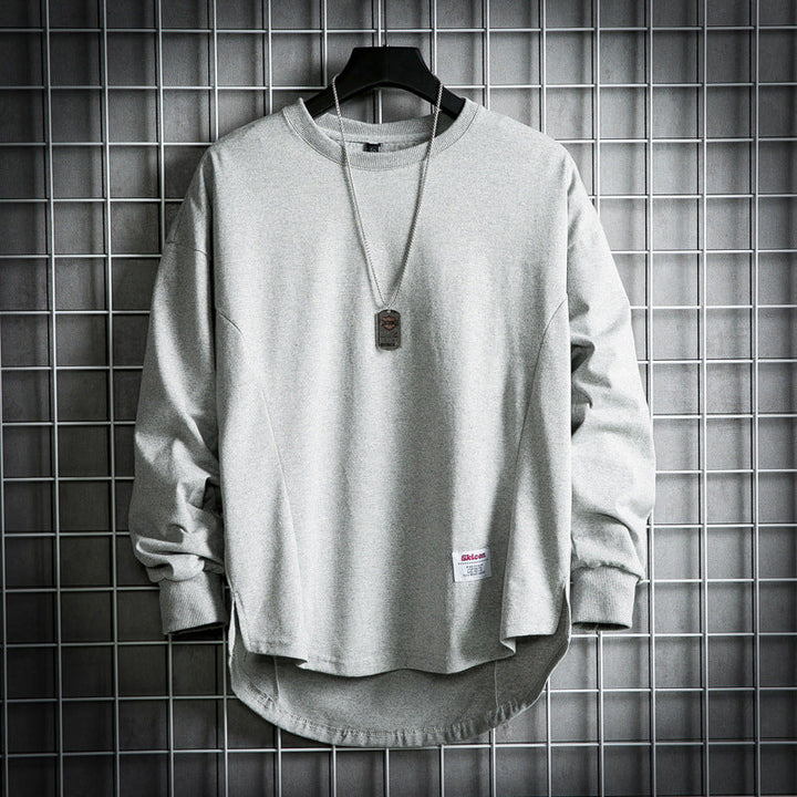 Front view of a light grey oversized cotton hooded sweater with a rounded hem and a dog tag necklace