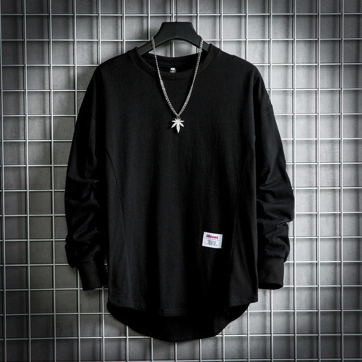 Front view of a black oversized cotton hooded sweater with a rounded hem and a necklace with a leaf pendant