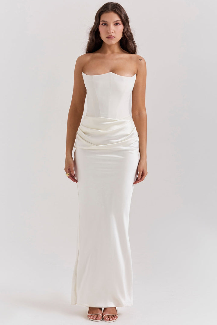 Front view of a model wearing a white strapless corset dress with a ruched waist and long skirt