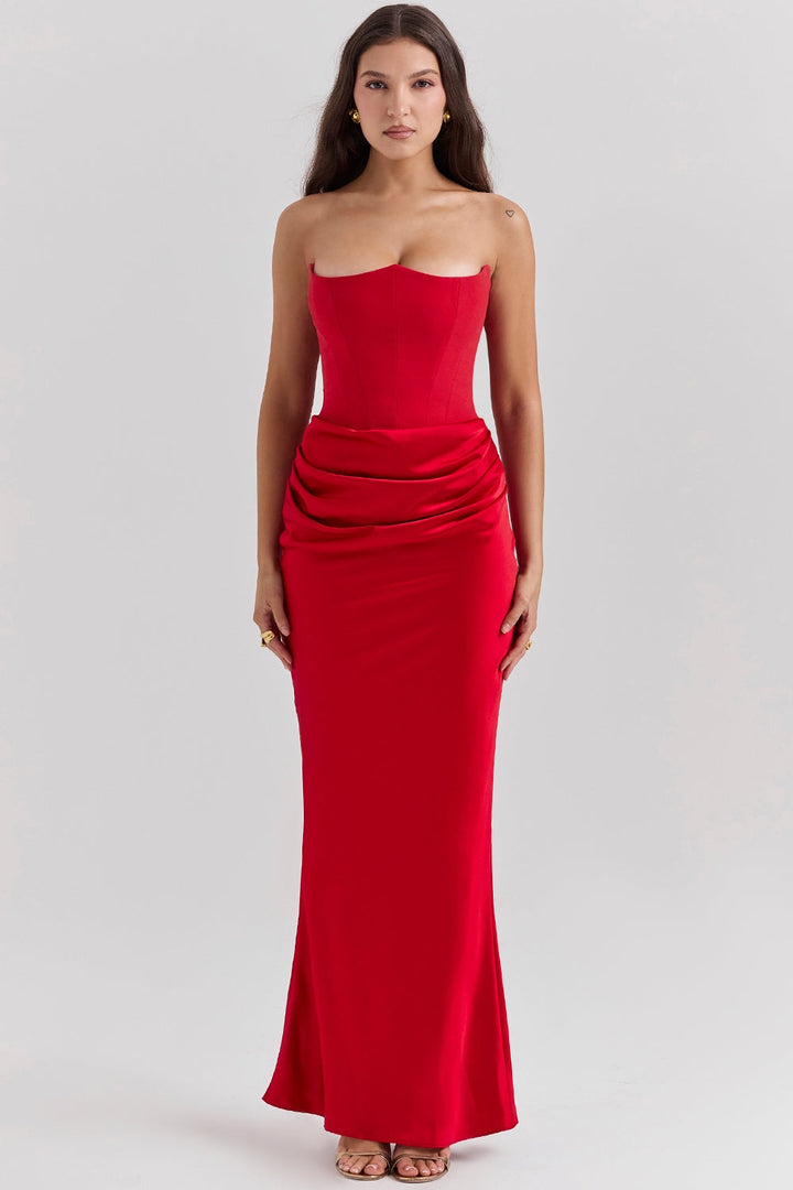 Front view of a model wearing a red strapless corset dress with a ruched waist and long flowing skirt