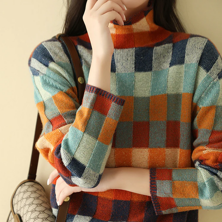 Close up, model wearing a colourful checkered knit jumper with high neck and a shoulder bag