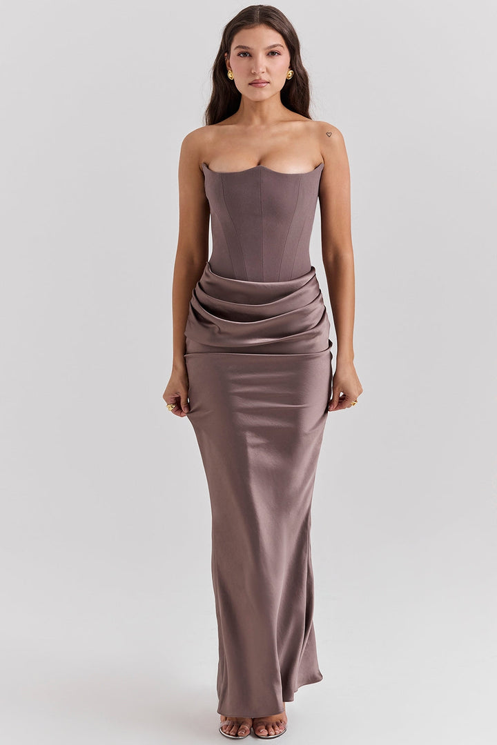 Front view of a model wearing a brown strapless corset dress with a ruched waist and long flowing skirt