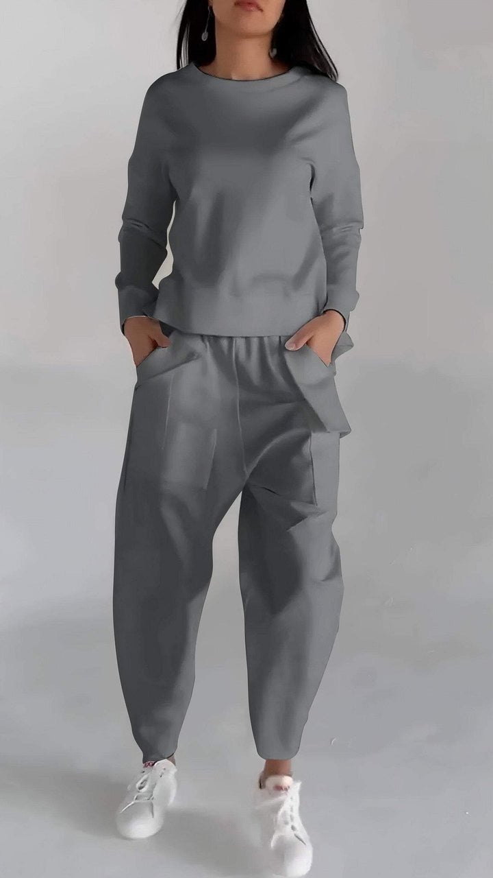 Front view, model wearing a grey loose fit Elena Two-Piece Set, hands in pockets, wearing white sneakers