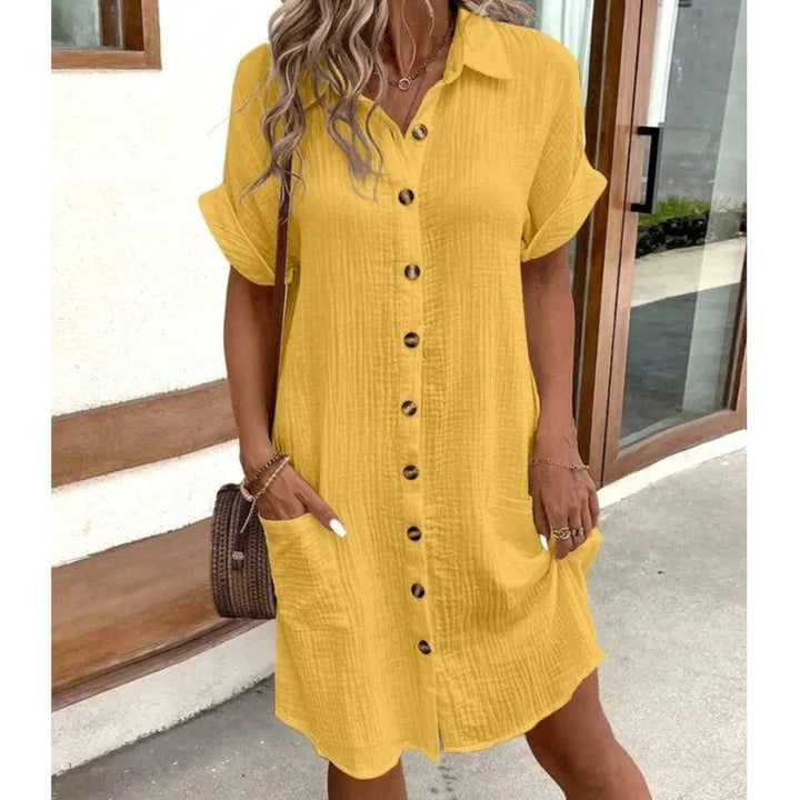 Front view of a model wearing a yellow collared summer dress with short sleeves, front buttons, and two pockets