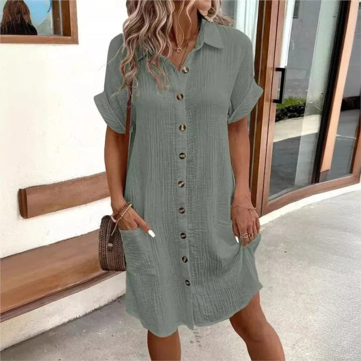 Front view of a model wearing a green collared summer dress with short sleeves, front buttons, and two pockets
