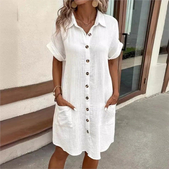 Close up front view of a model wearing the white collared summer dress with hands in pockets