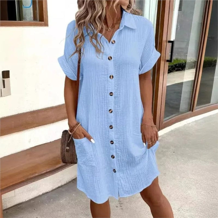 Front view of a model wearing a light blue collared summer dress with short sleeves and two front pockets