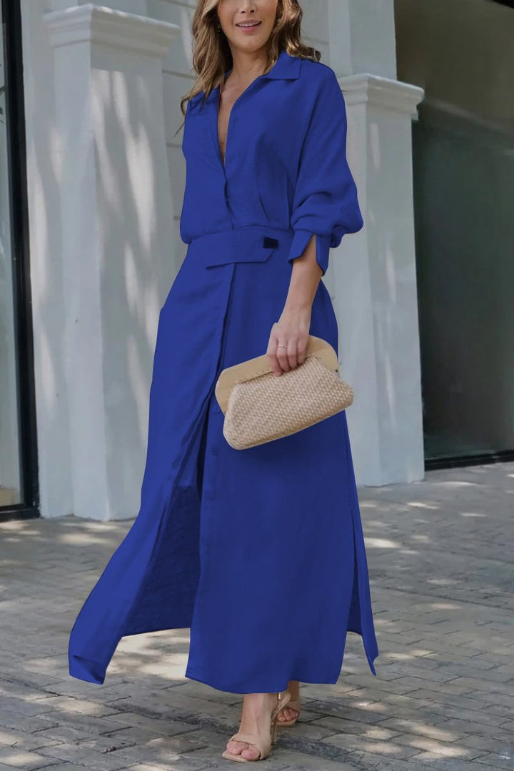 Front view of a model wearing a royal blue solid colour maxi shirt dress with a woven clutch bag