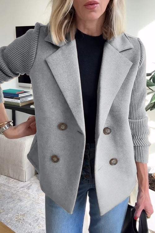 Front view of a model wearing the grey button patchwork sleeve casual coat over a black top and blue jeans