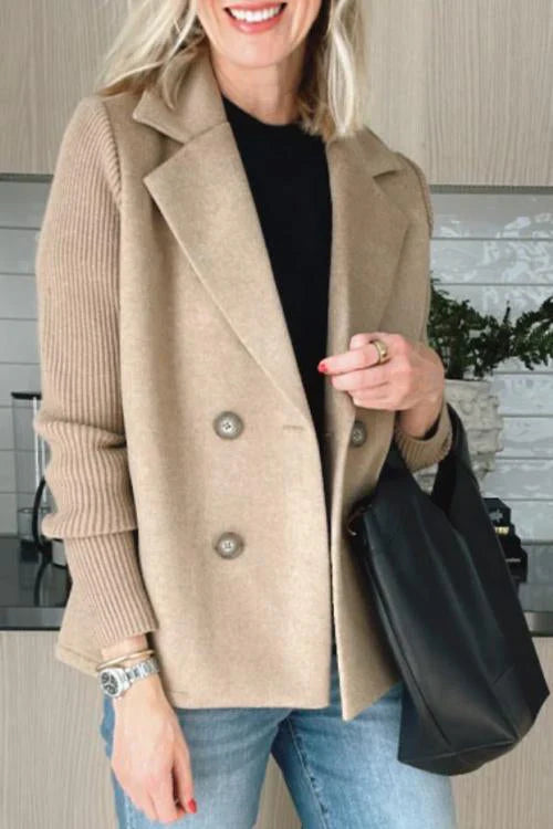 Close up of a model wearing the beige button patchwork sleeve casual coat with a black top and blue jeans