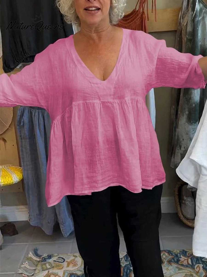 Front view of a woman wearing a pink 3/4 sleeve V-neck cotton linen shirt with gathered waist over black pants