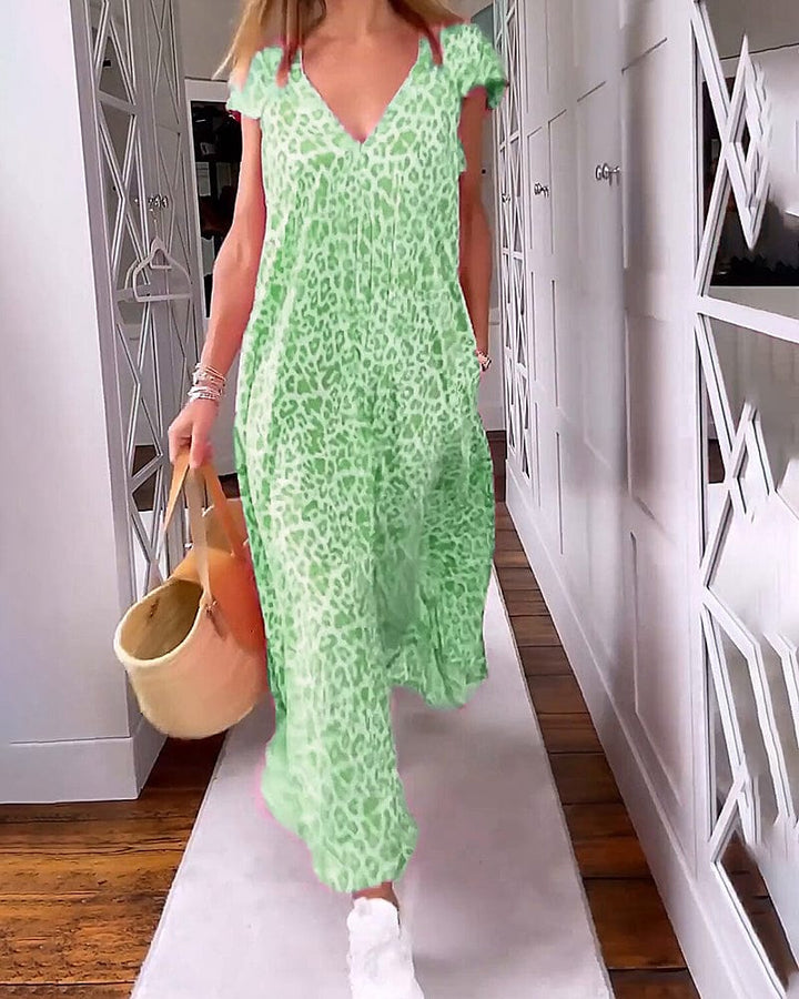Front view of a model in a leopard print maxi dress, walking and carrying a straw bag
