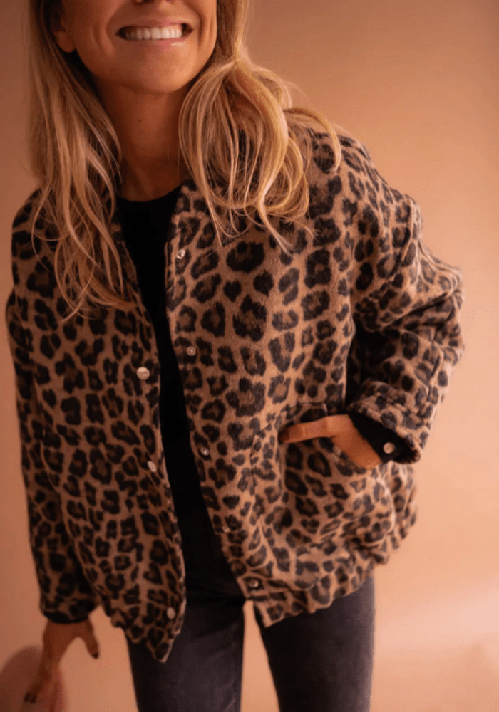 Front view of a woman wearing a leopard bomber jacket with her hand in the pocket