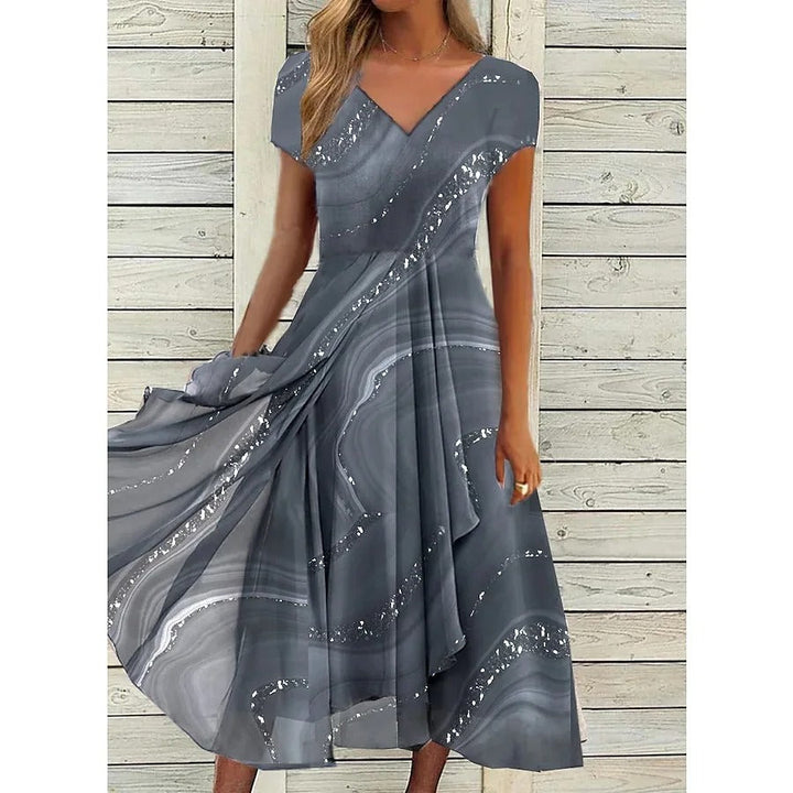 Front view worn by model of a V-neck midi dress with a grey abstract patchwork design and silver flecks