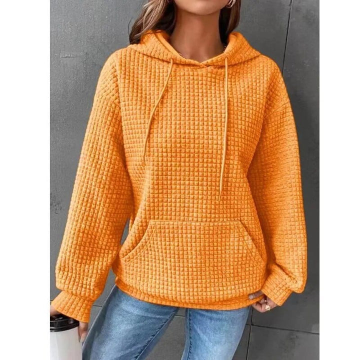 Front view of a model wearing the orange oversized cotton hoodie with waffle texture, drawstring, and front pocket