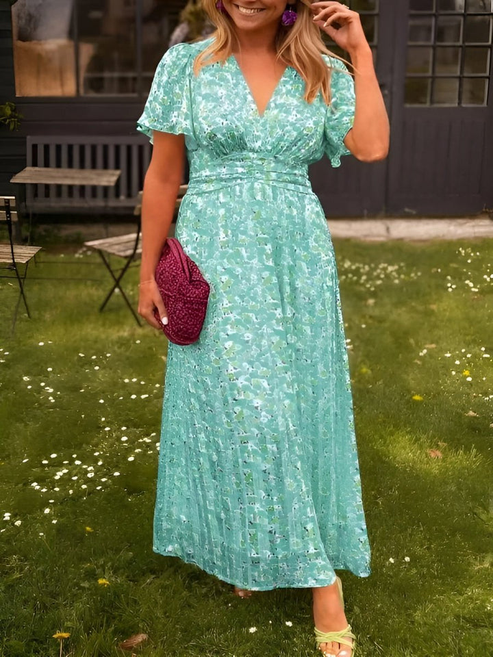 Worn by model, a woman in a garden wearing a summer floral print casual maxi dress and light green sandals