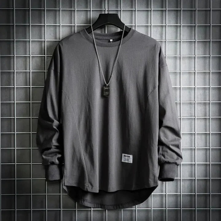 Front view of a dark grey oversized cotton hooded sweater with a rounded hem and a necklace