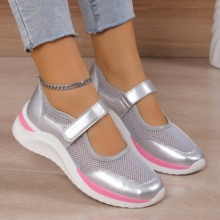 Front view of silver orthopedic Mary Jane shoes with mesh and pink accents on a model wearing light blue jeans