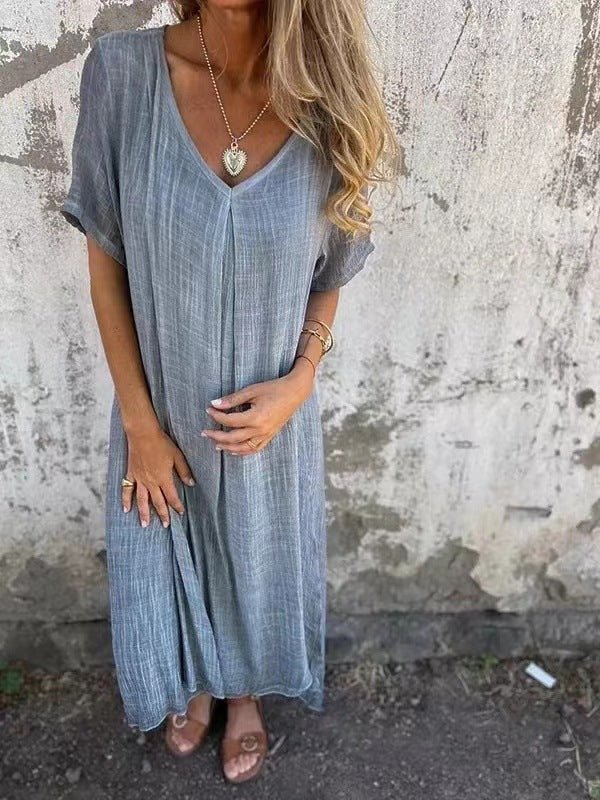 Front view of a model wearing the elegant midi V-neck summer dress in a soft sage green, with hands resting on the dress