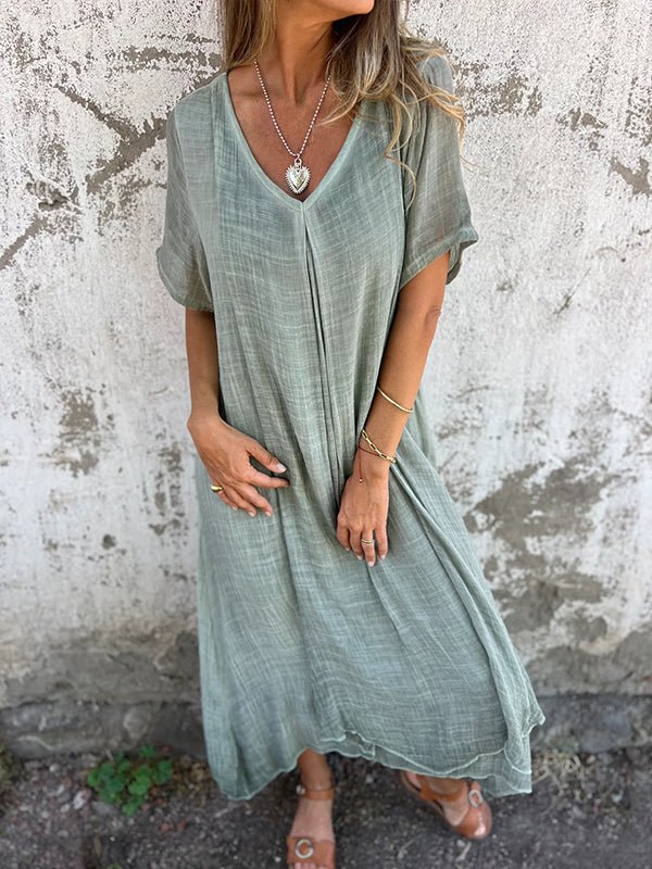 Three quarter length front view of a model wearing the elegant midi V-neck summer dress in a soft sage green