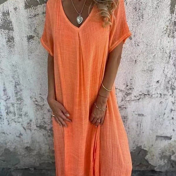 Front view of a model wearing the elegant midi V-neck summer dress in peach, with hands in pockets