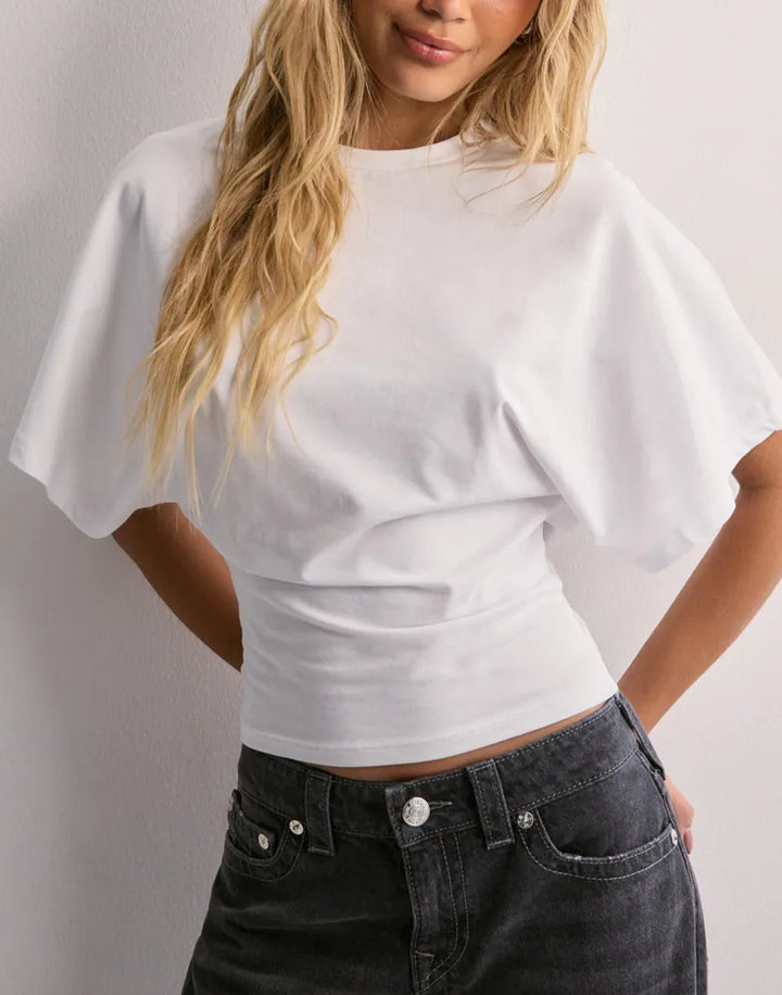 Close up front view of a model wearing a white oversized icon tee with wide sleeves and dark wash jeans